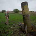 جندي أوكراني يسير بجوار بقايا صاروخ باليستي روسي سقط في حقل